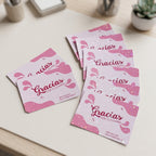 Varias tarjetas holográficas Gracias por tu compra desplegadas sobre un escritorio claro